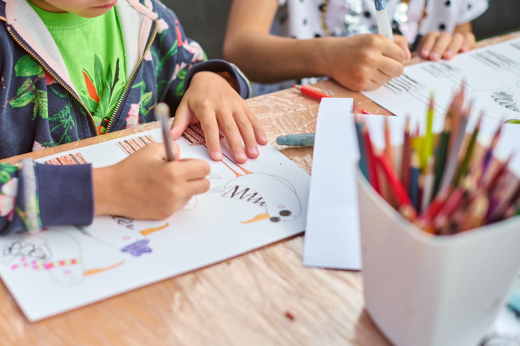 Child drawing with colors on wooden table
