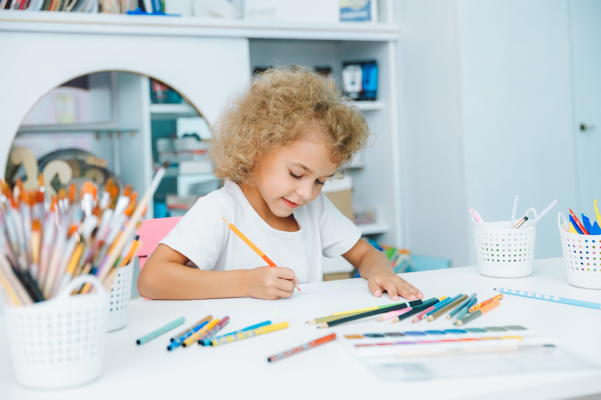 Cute little blonde preschooler girl draws at home