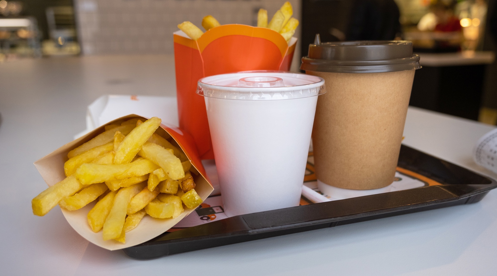 Fast food on a tray in a restaurant. French fries, a glass with a milkshake, coffee