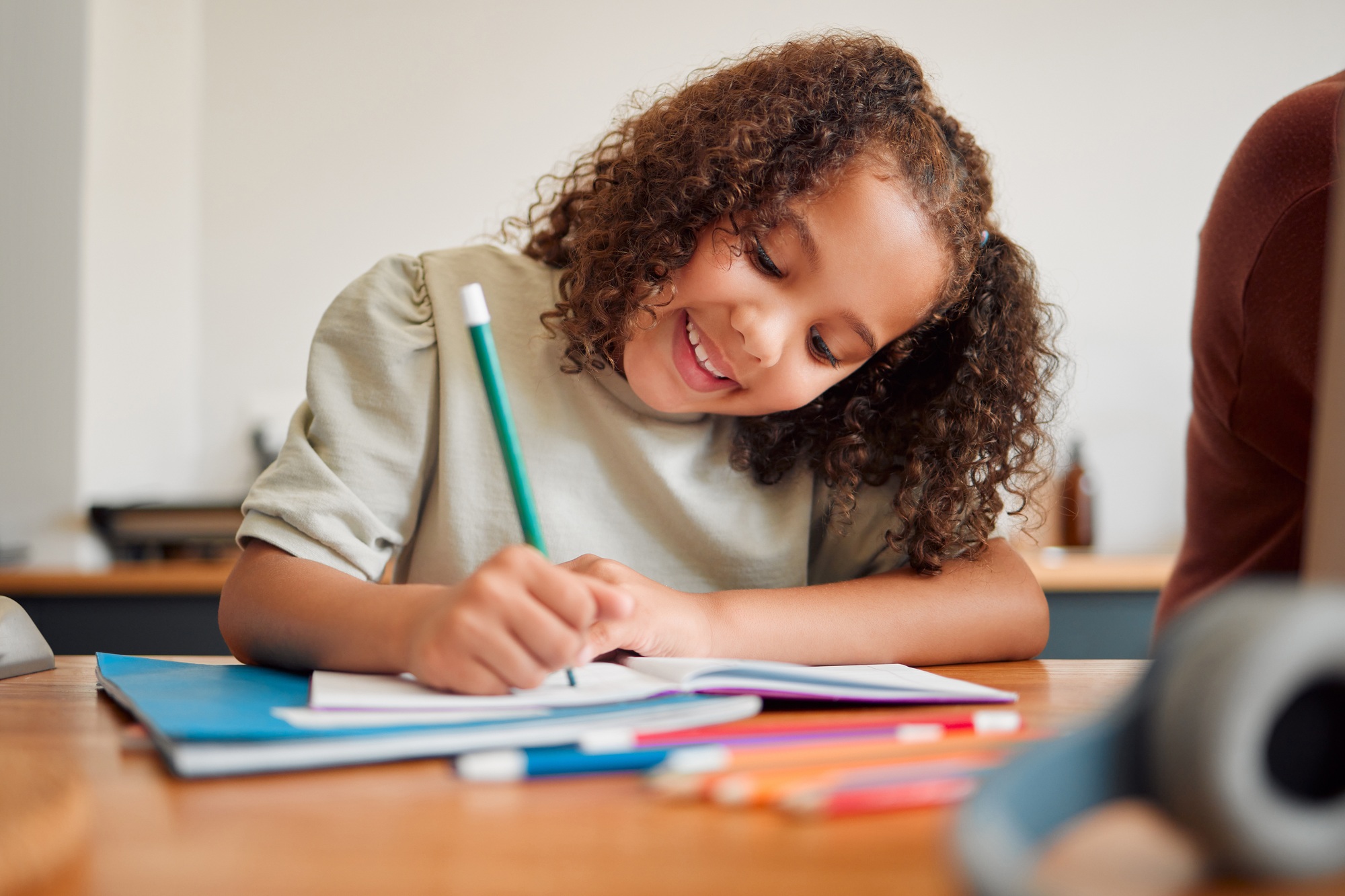 Learning, smiling and creative young girl drawing with a colorful pencil feeling happy and content.