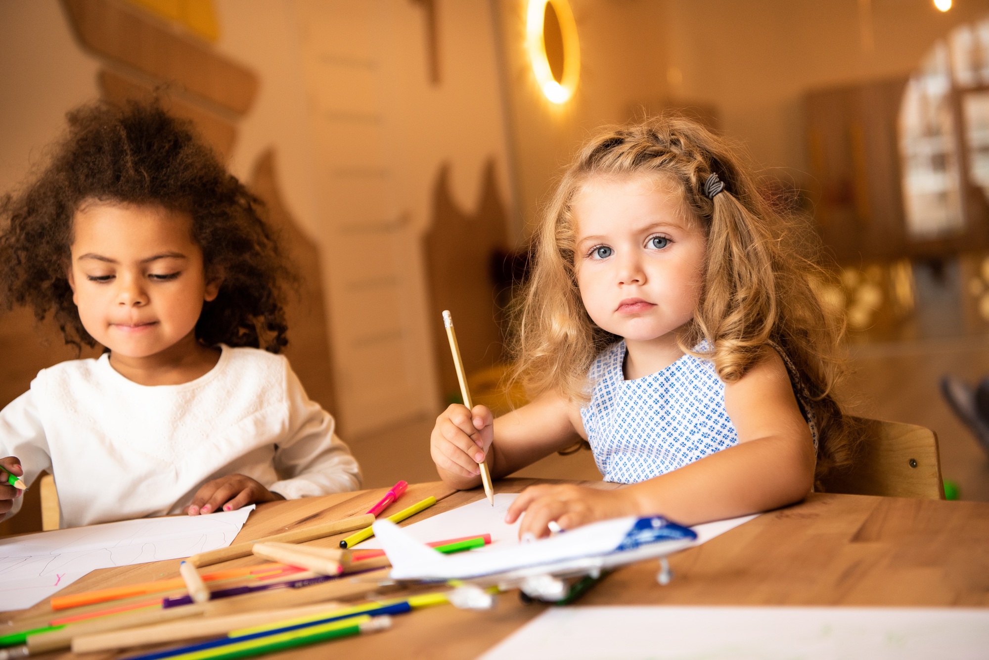 multicultural kids drawing with pencils in kindergarten